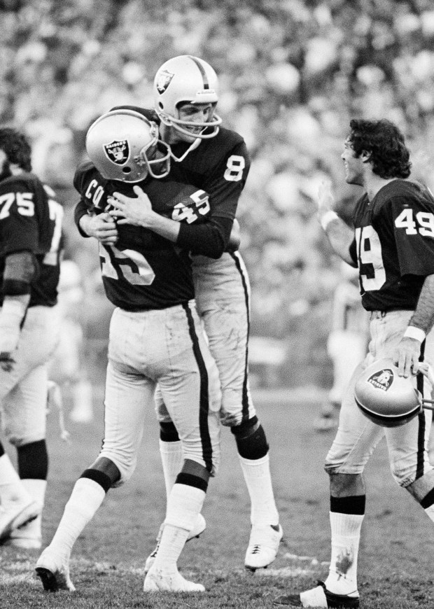 FILE - In this Dec. 28, 1975, file photo, Oakland Raiders kicker Ray Guy (8) is hugged by teammate Neal Colzie in the closing seconds of the Raiders 31-28 win over the Cincinnati Bengals in a divisional playoff game in Oakland, Calif. Those anxious seconds for punt returners awaiting his booming kicks were nothing compared to the more than two decades Guy had to endure before finally getting the call that he was elected to the Pro Football Hall of Fame. (AP Photo/File)