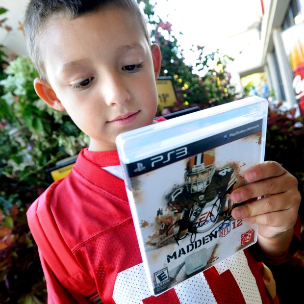Jordan Rutchena, 6, of Danville, looks at his new Madden NFL 12 video game, autographed by former San Francisco 49er Roger Craig, during a promotional event for the game at the Safeway grocery store in San Ramon, Calif., on Tuesday, Aug. 30, 2011. Madden NFL 12, made by game developer EA Sports, is available at the Blockbuster Express DVD machine located at the Safeway store. (Doug Duran/Staff)