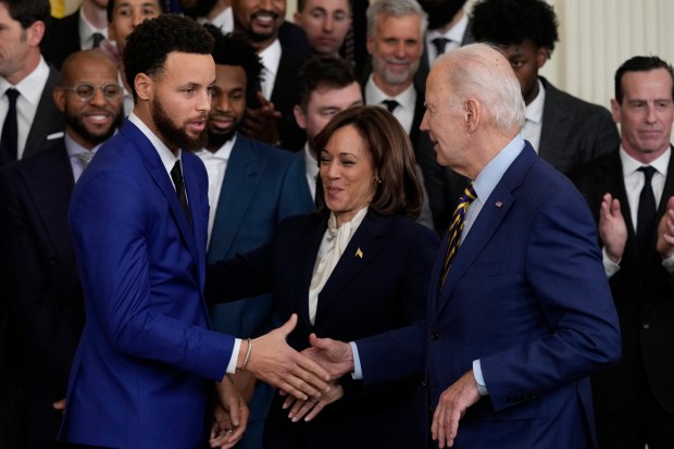 President Joe Biden shakes hands with Stephen Curry as Vice President Kamala Harris smiles as they welcome the 2022 NBA champions, the Golden State Warriors, to the East Room of the White House in Washington, Tuesday, Jan 17, 2023. (AP Photo/Susan Walsh)