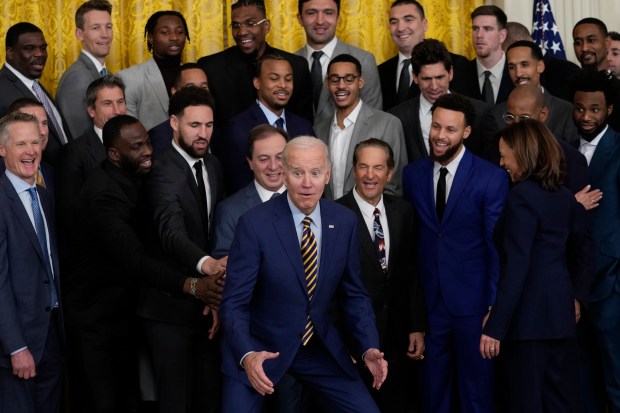 President Joe Biden reacts as he prepares to kneel for a group photo as he welcomes the 2022 NBA champions, the Golden State Warriors, to the East Room of the White House in Washington, Tuesday, Jan 17, 2023. (AP Photo/Susan Walsh)