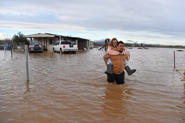 Ryan Orosco, of Brentwood, carries his wife Amanda Orosco, from their flooded home on Bixler Road in Brentwood, Calif., on Monday, Jan. 15, 2023. (Jose Carlos Fajardo/Bay Area News Group)