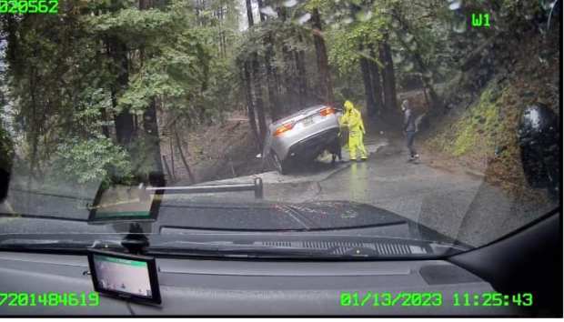 In images shared Friday, January 13, 2023, a California Highway Patrol officer helps people exit a car teetering on a cliffside's edge in the 800 block of Old Mill Pond Road in Los Gatos, Calif. (Courtesy California Highway Patrol)