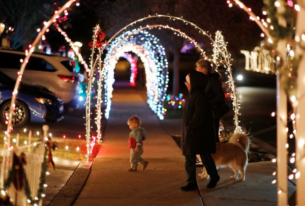 Avery MacDevitt, 16 months, her parents Sarah and Julian MacDevitt, grandmother Elizabeth Monte and dog Emma, walk through the Tunnels of Joy Christmas light displays in the Deer Ridge neighborhood of Brentwood, Calif., on Thursday, Dec. 8, 2022. This year's event will raise money for Cristian Munoz, 11, who was recently diagnosed with stage 3 kidney cancer. (Jane Tyska/Bay Area News Group)