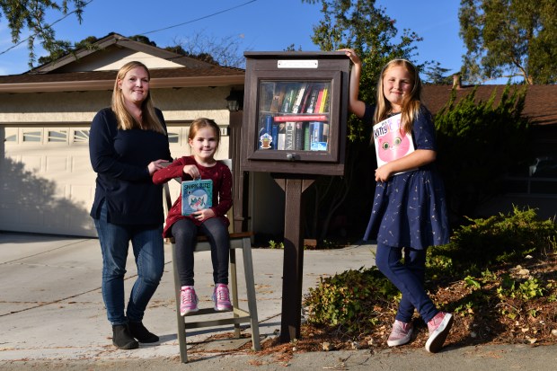 Nicole Botha, of Pinole, stands next to her Little Free Library with her daughters Kimberley, 4, and Ashlyn, 8, in front of her home in Pinole, Calif., on Thursday, Nov. 10, 2022. Botha built her Little Free Library in June 2019. She loves to read and sometimes picks up books at Goodwill. When she's done reading the books she places them in her Little Free Library. On some occasions passing motorist drop off boxes of books in front of her home and if Botha likes them she'll read them and place those books in her Little Free Library as well. (Jose Carlos Fajardo/Bay Area News Group)