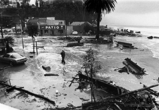 A man walks through floodwaters amid severe damage to Capitola Village from a 1983 storm (courtesy of Capitola Historical Museum -- Dennis Noonan photo)