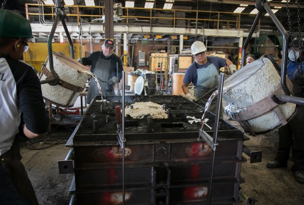 Grinder Dave Devencenzi (L) and molder Rigo Garcia (R) help pour molten aluminum into a flask to make a casting for client KLA Tencor at the Kearney Pattern Works and Foundry in San Jose on Friday, August 17, 2018. This is the last casting the foundry will make after agreeing to sell the company's property to Google. (LiPo Ching/Bay Area News Group)