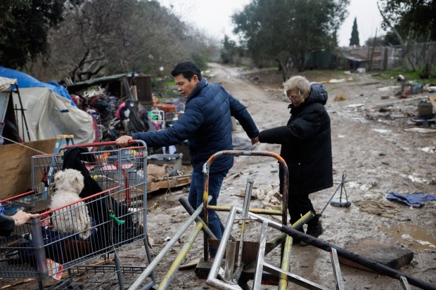 San Jose Councilmember for District 7 Bien Doan, left, holds the hand of Janet Parks Swanson, 63, who is unhoused, as Swanson is escorted out from a homeless encampment along Coyote Creek at Tully Road on Wednesday, Jan. 4, 2022, in San Jose, Calif. A ruthless winter storm bore down on the Bay Area and Northern California on Wednesday, prompting emergency proclamations, school closures and multiple hazard warnings of potential flooding, debris flows and severe winds. (Dai Sugano/Bay Area News Group)
