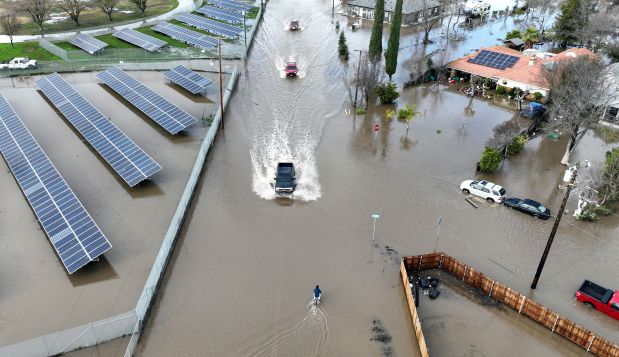 Cars drive through a flooded roadway in Planada, California, as an atmospheric river continues soaking the Golden State on January 10, 2023. (Photo by Josh Edelson/AFP via Getty Images)