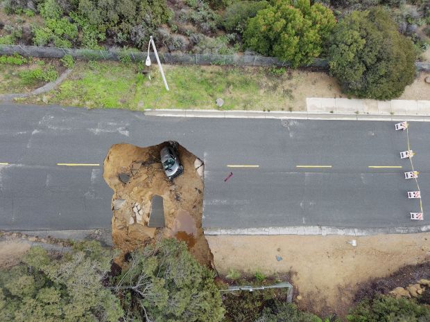 Two cars plunged into a large sinkhole that opened during a day of relentless rain on January 10, 2023 in the Chatsworth neighborhood of Los Angeles, California. (Photo by Robyn Beck/AFP via Getty Images)