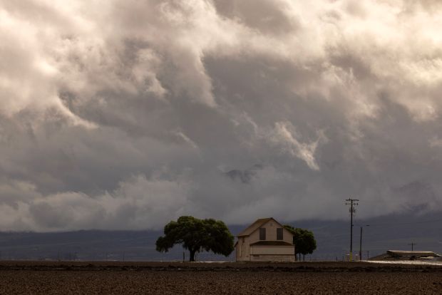 Clouds rise behind a farm near the flooded Salines River during a brief in a storm close to Chualar, California, on January 14, 2023. (Photo by David McNew/AFP via Getty Images)