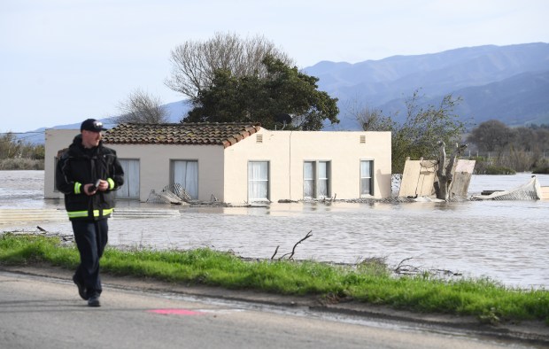 Cal Fire Caption Curtis Rhodes, walks past a home flooded by the Salinas River on Chualar Road near Chualar, Calif., on Thursday, Jan. 12, 2023. The Monterey County Sheriff's Office ordered additional evacuations for low-lying areas along the Salinas River in preparation of floods that could potentially close overland routes. (Doug Duran/Bay Area News Group)