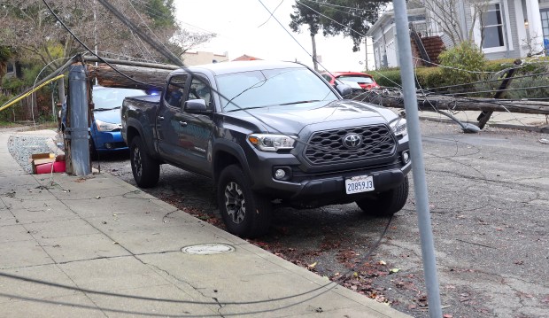 A broken utility pole lays across the back of a vehicle blocking Bella Vista Avenue on Wednesday, Jan. 4, 2023 in Oakland, Calif. (Aric Crabb/Bay Area News Group)