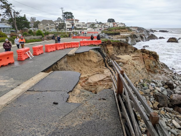 People walking along West Cliff Drive in Santa Cruz near Woodrow Avenue on Sunday afternoon Jan. 8, 2023 look at a large section of cliff that collapsed in recent storms, destroying part of the popular bike path and undermining the West Cliff Drive. (Paul Rogers / Bay Area News Group)