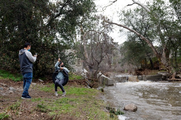 Juan Alexander takes a picture of Belen Cortez, as they stop at the Penitencia Creek. The creek has a strong flow during a break in the rain in San Jose, Calif., on Sunday, Jan. 8, 2023. (Josie Lepe for Bay Area News Group)